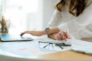 Businesswoman using calculator and laptop computer for analysis maketing plan, Accountant calculate financial report, computer with graph chart. Business, Finance and Accounting concept photo