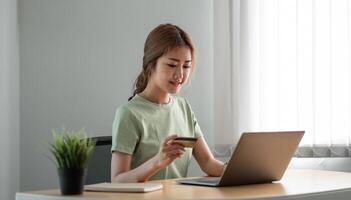 Happy woman doing online shopping at home, woman hand holding credit card and using laptop computer photo