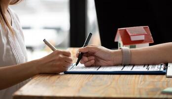 close up view hands of businessman signing leasing home documents and have a apartment keys on paperwork photo