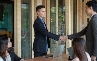 Group business people handshake at meeting table in office together with confident. Young businessman and businesswoman workers express agreement of investment deal photo