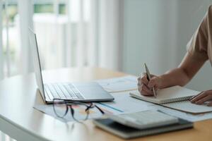 accountant woman working audit and calculating expense financial annual financial report balance sheet statement, doing finance making notes on paper checking document. photo