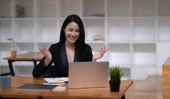 Happy asian woman communicate by call on computer working from home. Smiling businesswoman talking by conference, online virtual meeting using computer photo