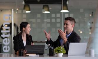 Asian and caucasian businesspeople learn new business app, apprentice listen associate tell about corporate program. Multiracial client and bank manager at business meeting using laptop negotiating photo