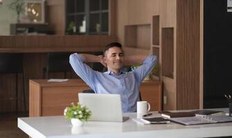 Relaxed calm caucasian businessman resting sit at office desk after working for financial with laptop computer. photo