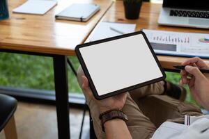 Cropped shot of a man sitting at modern office room and using blank white screen tablet, businessman using pen stylus photo