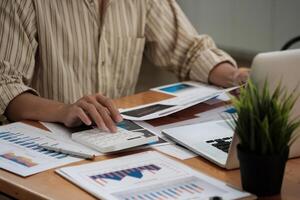 Close up hand of accountant working with computer and calculator for business and financial expense photo