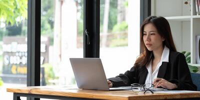 Close up of businesswoman or accountant hand holding pen working on calculator to calculate business data, accountancy document and laptop computer at office, business concept. photo