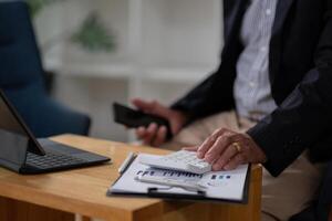 Close up hand of elderly accountant working on desk using calculator for calculate finance report in office. Businessman calculating business balance prepare tax reduction photo