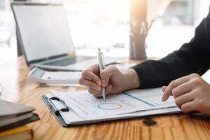 Businesswoman discussing analysis charts or graphs on desk table and using laptop computer. Close up female analysis and strategy concept photo