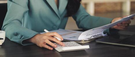 Close up asian accountant working and analyzing financial reports project accounting with chart graph and calculator photo