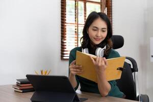 Smiling girl student wear headphone study online with laptop computer, happy young woman learn language listen lecture watch webinar write notes look at laptop sit in cafe, distant education photo