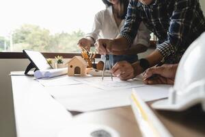 Close up of engineer hand drawing plan on blue print with architect equipment, Architects discussing at the table, team work and work flow construction concept. photo