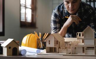 Engineer architect designer freelance work on start-up project with home model, construction plan. architect design working drawing sketch plans blueprints and making construction model. Architects photo