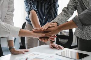 Close up happy diverse business people putting hands together, showing support and unity. Multiracial colleagues involved in team building activity. Staff training concept, start working together. photo