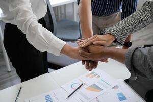 Close up happy diverse business people putting hands together, showing support and unity. Multiracial colleagues involved in team building activity. Staff training concept, start working together. photo