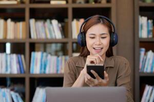 Asian tutor of language start online lesson with trainee wave hand smiling looks at pc screen. woman in headphones communicating distantly, e-learning process, application usage concept photo