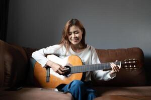 Image of happy beautiful woman playing guitar and composing song photo