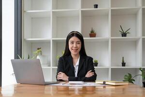 Portrait confidence asian business woman looking on camera sitting at work desk in office. photo