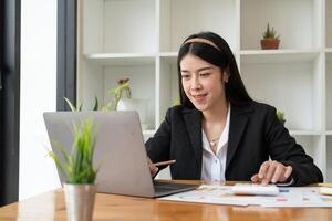 Businesswoman using calculator for analysis maketing plan, Accountant calculate financial report, computer with graph chart. Business, Finance and Accounting concepts photo