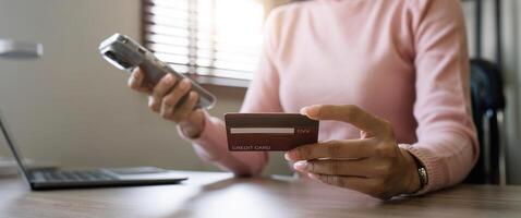 Close up young woman makes an online payment for a purchase with credit card. Online shopping with mobile phone. photo