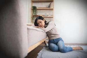 joven solitario atractivo asiático mujer llorando en sofá sensación triste cansado y preocupado sufrimiento depresión aislado a hogar. mental salud y aislamiento, estrés, desempleo y desconsolado concepto. foto