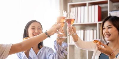 Group of Asian friends gather to celebrate Christmas with champagne and eating pizza at home. Joy of holiday party with friends or colleague concept photo