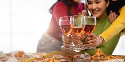 Group of Asian friends gather to celebrate Christmas with champagne and eating pizza at home. Joy of holiday party with friends or colleague concept photo