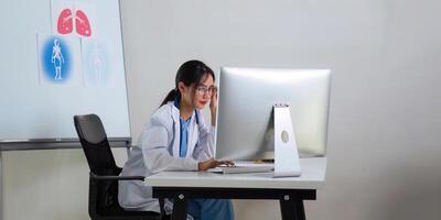 Female doctor a works at a computer while there were many medicine bottles on the table while sitting at a work desk photo