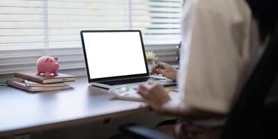 Laptop screen mock up, laptop in blank empty screen on the desk in home while woman working on financial calculating photo