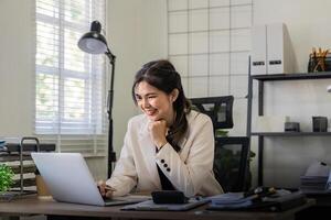 Businesswoman smiling confident using laptop computer working on financial statistics with graph document female accountant analysis data at office photo