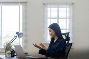 Young asian businesswoman using a calculator to calculate business principle. Accounting statistics concept at the office photo
