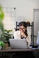 Businesswoman smiling confident using laptop computer working on financial statistics with graph document female accountant analysis data at office photo