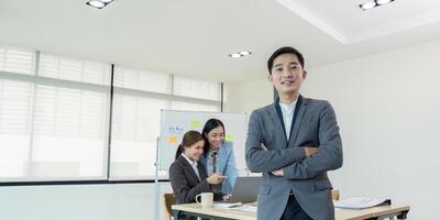 Confident business leader with team working on laptop in office. Concept of leadership and teamwork photo