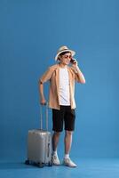 Portrait of Asian man posing on blue background, traveling in summer photo