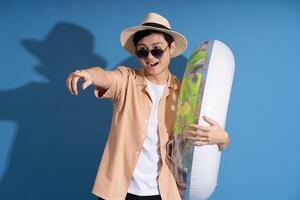 Portrait of Asian man posing on blue background, traveling in summer photo