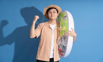 Portrait of Asian man posing on blue background, traveling in summer photo