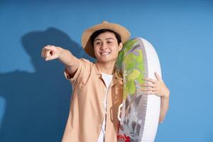 Portrait of Asian man posing on blue background, traveling in summer photo