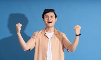 Portrait of Asian man posing on blue background, traveling in summer photo