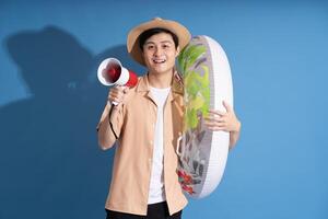 Portrait of Asian man posing on blue background, traveling in summer photo