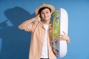 Portrait of Asian man posing on blue background, traveling in summer photo