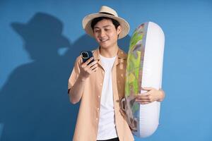 Portrait of Asian man posing on blue background, traveling in summer photo