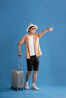 Portrait of Asian man posing on blue background, traveling in summer photo