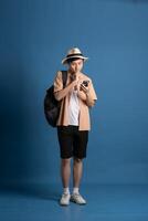 Portrait of Asian man posing on blue background, traveling in summer photo