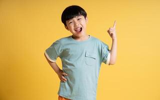 Portrait of adorable asian boy posing on yellow background photo