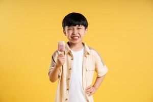 Portrait of adorable asian boy posing on yellow background photo