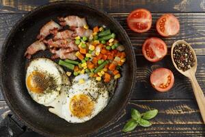 Fried eggs with vegetables in a pan. photo