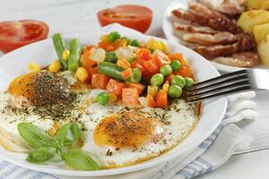 Fried eggs with vegetables. Traditional delicious breakfast and lunch. photo