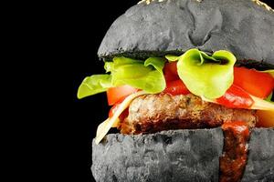 Black burger close-up. Burger with tomatoes, greens, onions and meat. place for text cope space photo