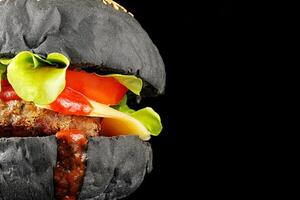 Black burger close-up. Burger with tomatoes, greens, onions and meat. place for text cope space photo