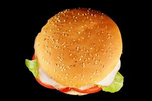burger with lettuce, tomato, cheese and cutlet top view. Classic cheeseburger with beef, cheese, tomato on black background. Top view. photo